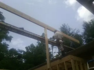Carpenter setting a ridge beam over a new addition frame — Ice Dam Removal by Roofing Brothers in Mottville