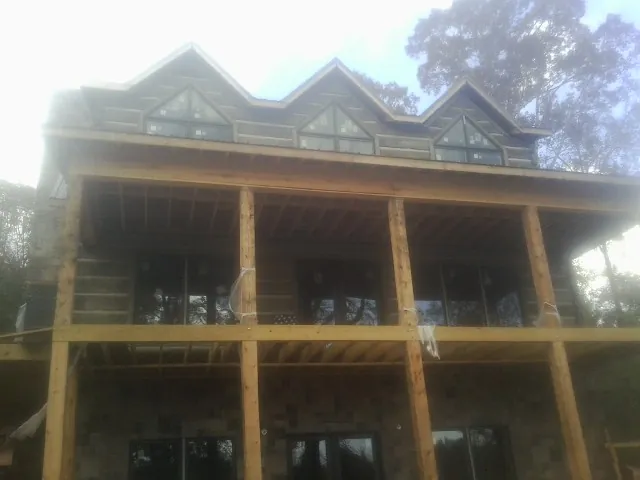 Dormers and porch framing on a large log home under construction — Roof Coating work by our crew in Mottville