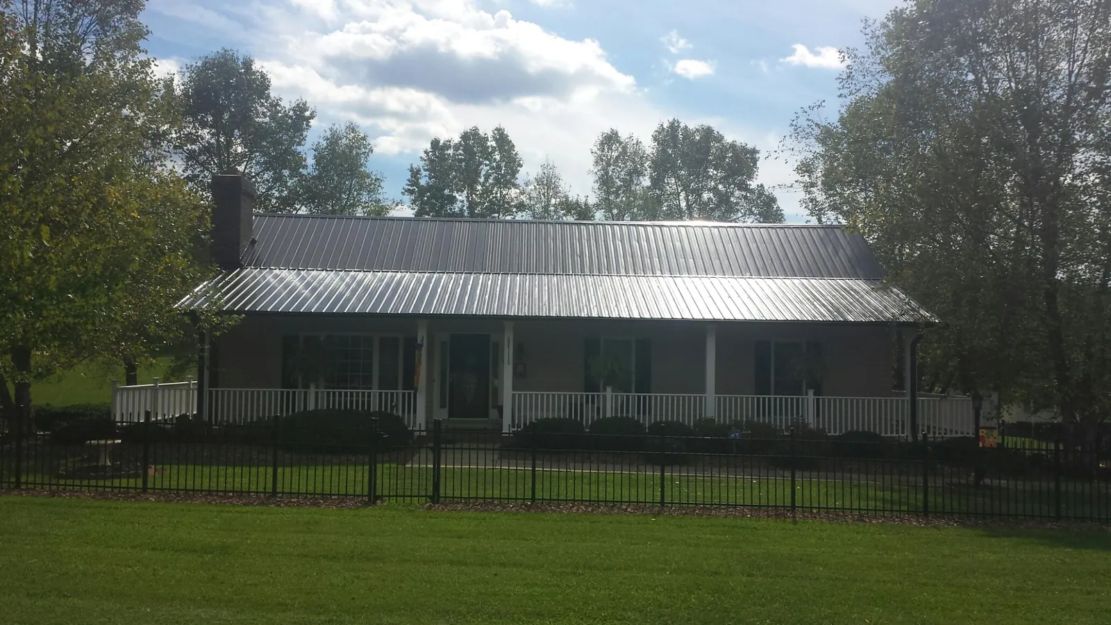 Gray metal roof on a brick ranch with a full width front porch — Gutter Guard Installation work by our crew in Mottville