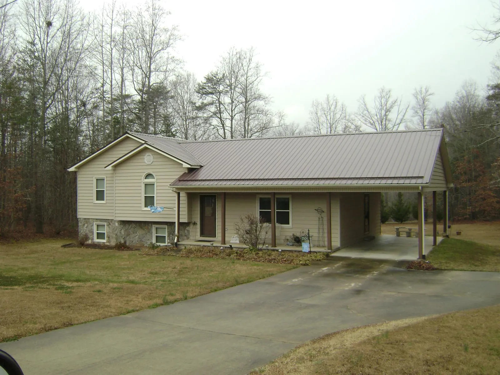 Brown metal roof on a tan split level home with an attached carport in Mottville