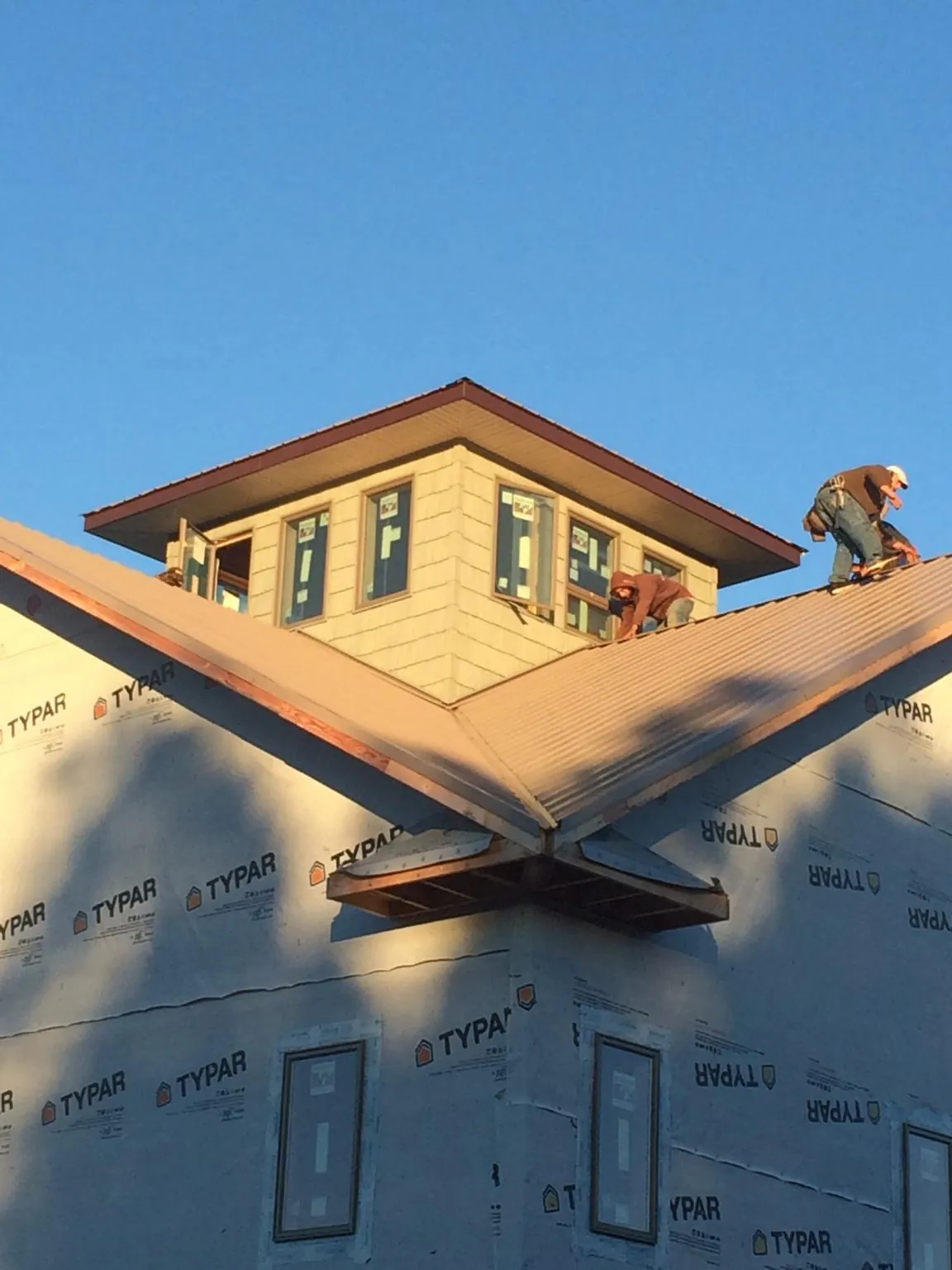 Roofers working around a rooftop cupola on a new metal roof at sunset — Roof Waterproofing in Mottville by Roofing Brothers